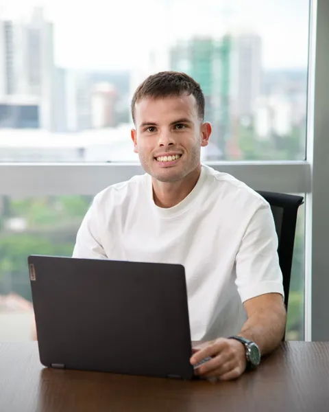 Leandro Canet, asistente comercial de Artola & Cía, sonriendo frente a su notebook en la oficina