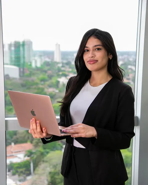 Micaela Burgos, de back office de Artola & Cía, sonriendo junto a la ventana de la oficina