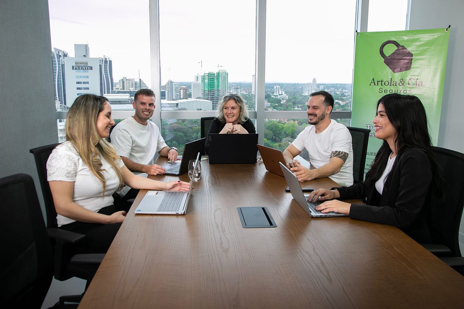 Equipo de Artola & Cía reunido alrededor de la mesa de la oficina