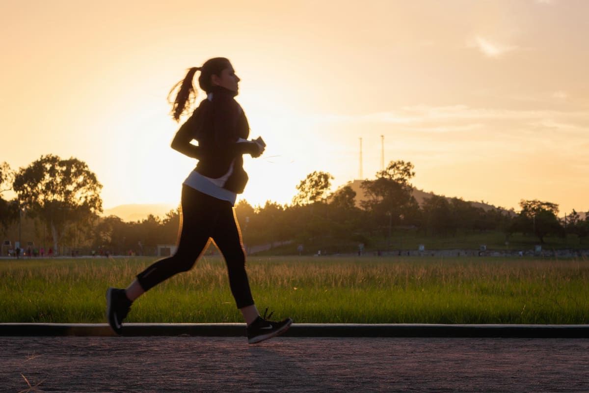 Mujer corriendo en un parque al atardecer
